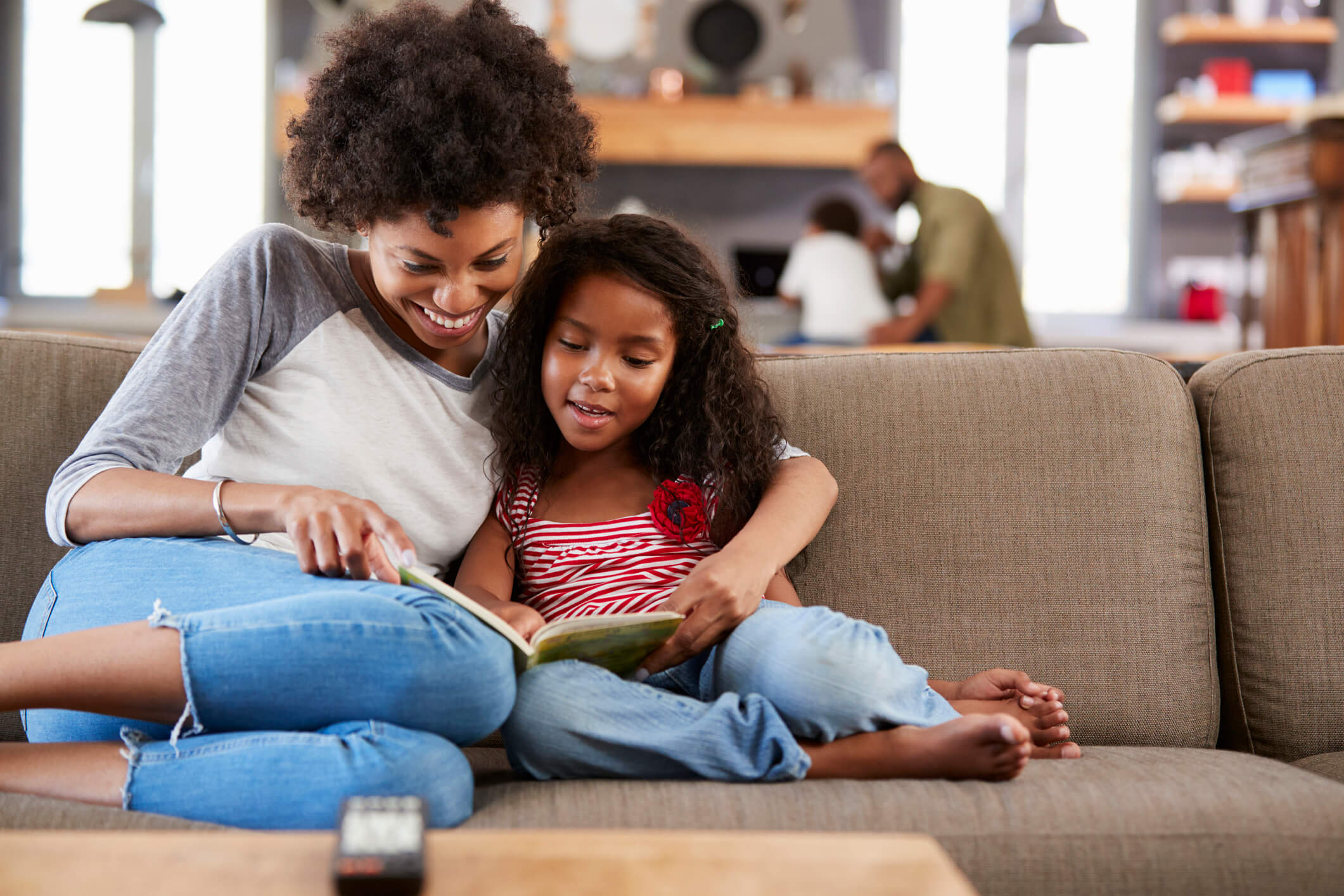 Mum and daughter reading a book on sofa