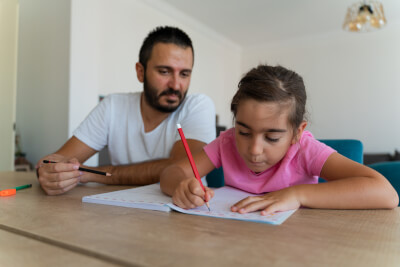 father and primary-age daugther working together on a maths homework problem
