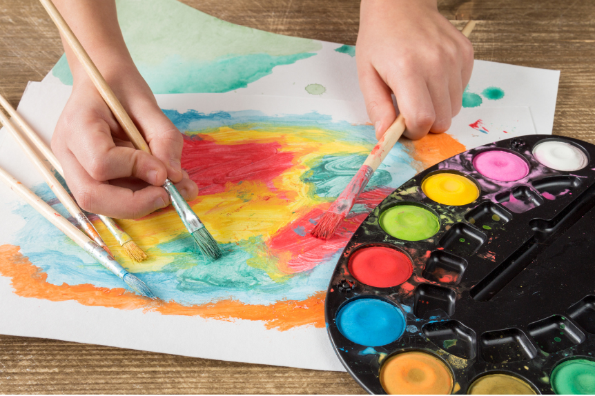 Close up of child's hand painting on paper